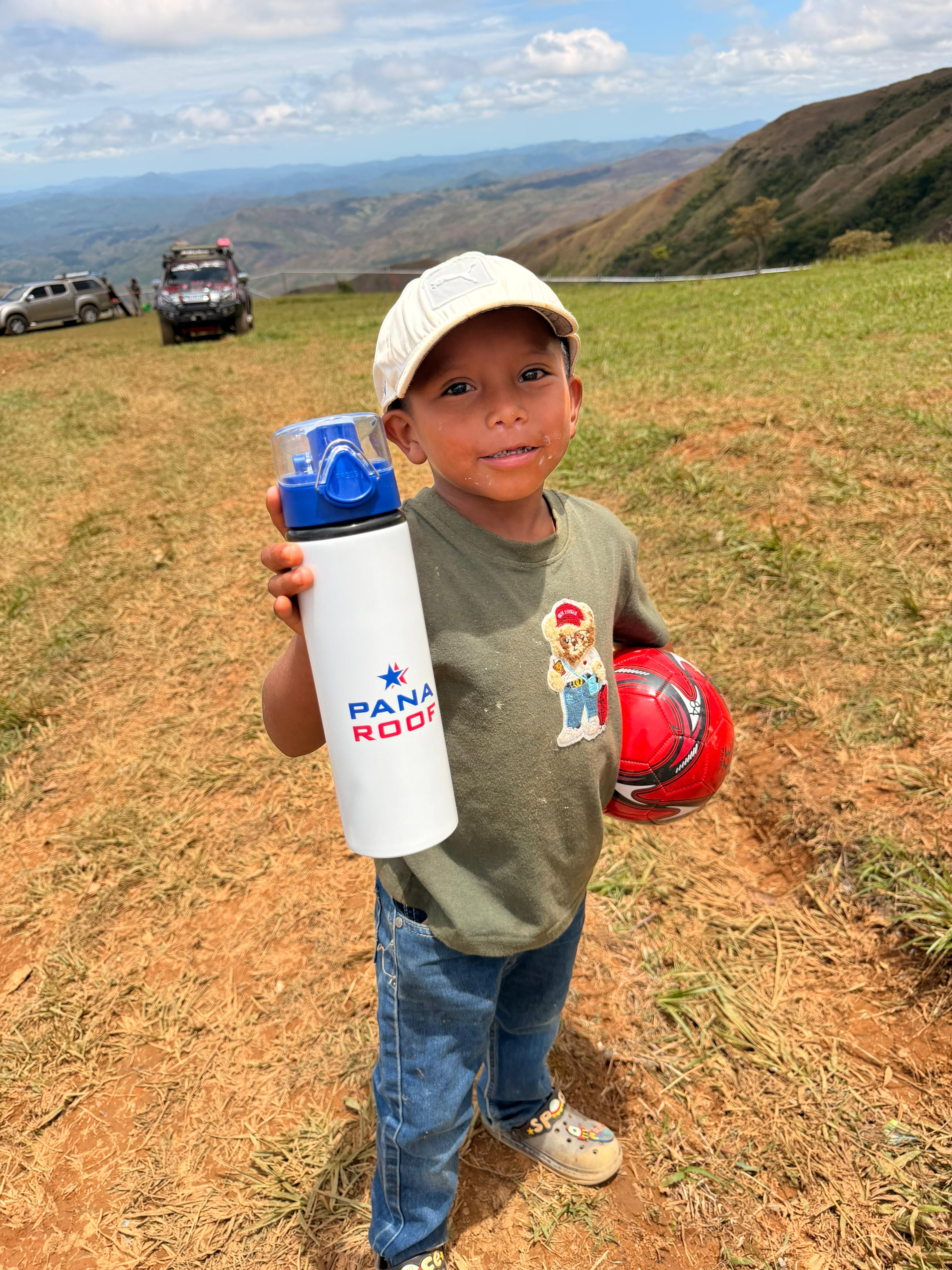 Niño con un balón y una botella Pana Roof durante una actividad comunitaria
